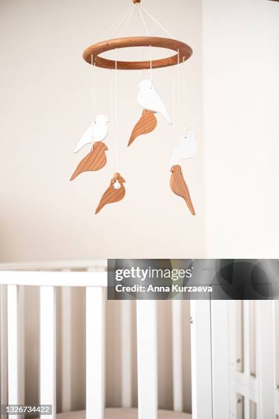 close up view of baby room with a white baby bed and a baby mobile hanging over the bed, selective focus. nursery interior. - mobile imagens e fotografias de stock