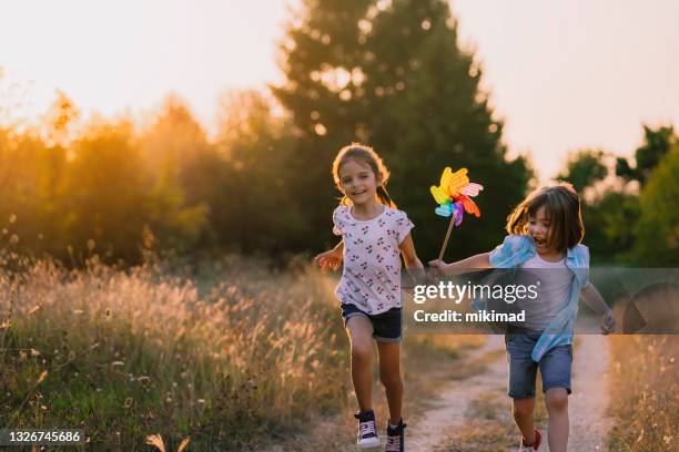 happy kids having fun with pinwheel in the nature. running kids - the whirligig stockfoto's en -beelden