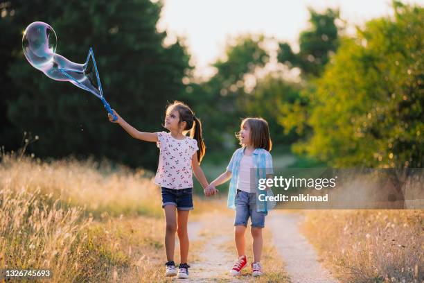 happy kids having fun with soap bubbles in the nature. running kids - bubbles happy stockfoto's en -beelden