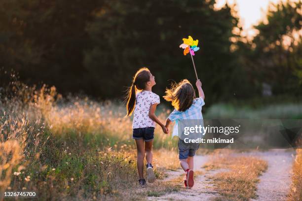 happy kids s’amusant avec pinwheel dans la nature. enfants qui courent - famille avec enfants photos et images de collection