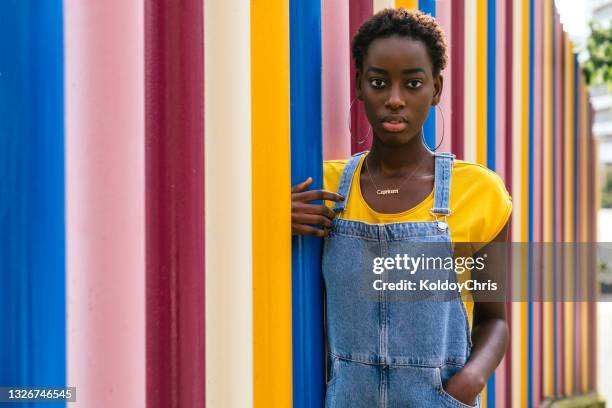 woman holding on to a colorful pole with a colorful background - pendant - fotografias e filmes do acervo