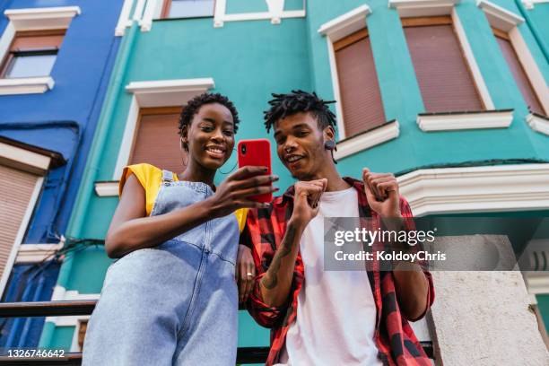 low angle view of african-american friends using phone - red stock photos et images de collection