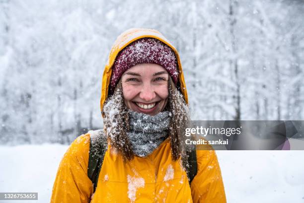 winter portrait of a laughing woman in yellow jacket at blizzard. - face snow stockfoto's en -beelden