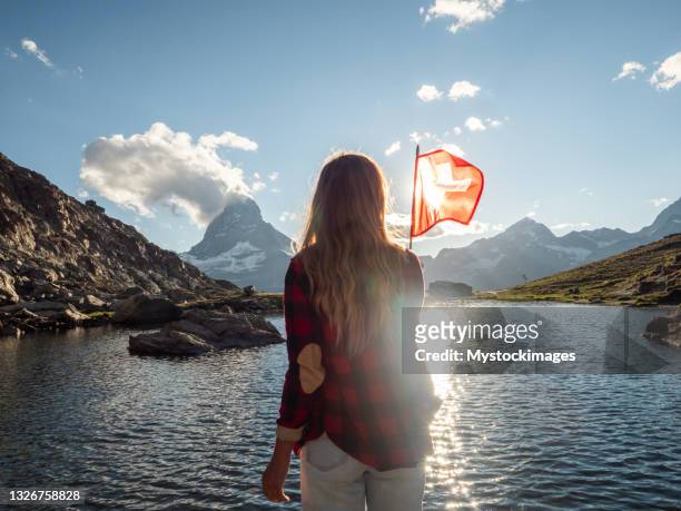 woman holds swiss flag against mountain landscape, zermatt - national holiday stockfoto's en -beelden