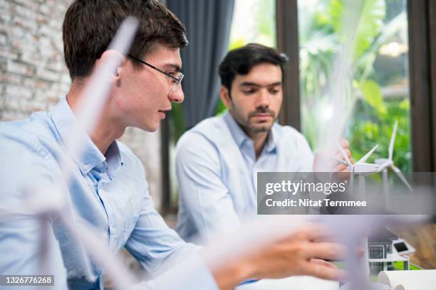 close-up of businessman discussing a wind turbine model for renewable energy solution development. green energy for future concepts. - investment research stock pictures, royalty-free photos & images