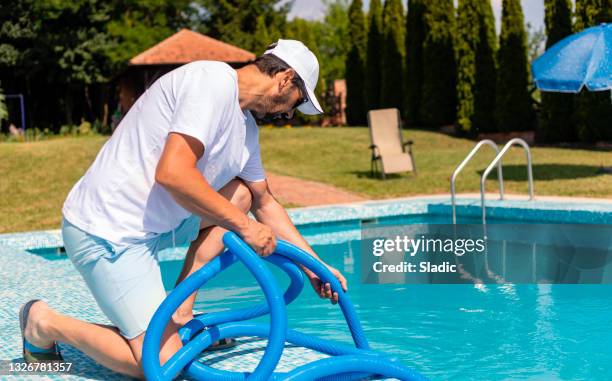 man cleaning the swimming pool - swimming pool maintenance stock pictures, royalty-free photos & images