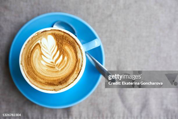 a blue cup of coffee with cappuccino with a beautiful art pattern on the foam on a linen napkin. - latte art ストックフォトと画像