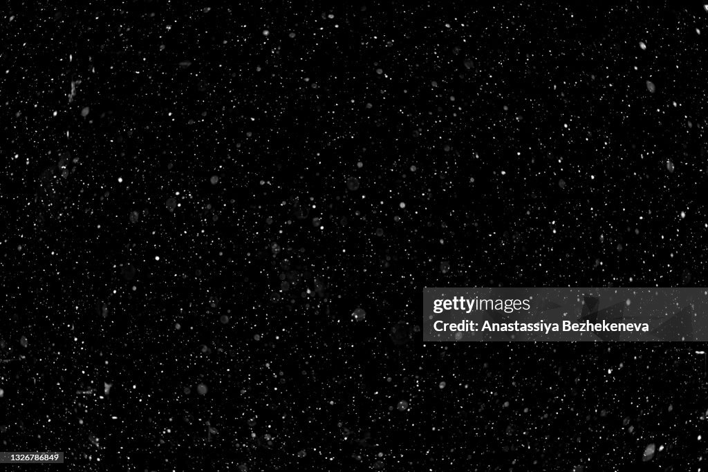 Falling white snow on black background