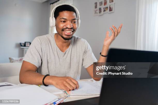 junger mann mit kopfhörer nund laptop mit online-schulklasse zu hause - budget hearing stock-fotos und bilder