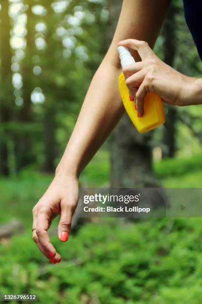 person spraying mosquito insect repellent in the forest, insect protection. - fly spray stock pictures, royalty-free photos & images