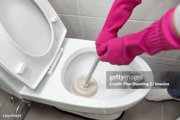a man unclogging toilet - toilet bowl stock pictures, royalty-free photos & images