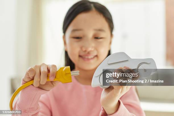 a smiling girl holding toy car and plug - tesla model s stock pictures, royalty-free photos & images