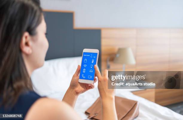 donna d'affari che utilizza l'applicazione smart room sullo schermo dello smartphone i̇n hotel room - wireless technology foto e immagini stock