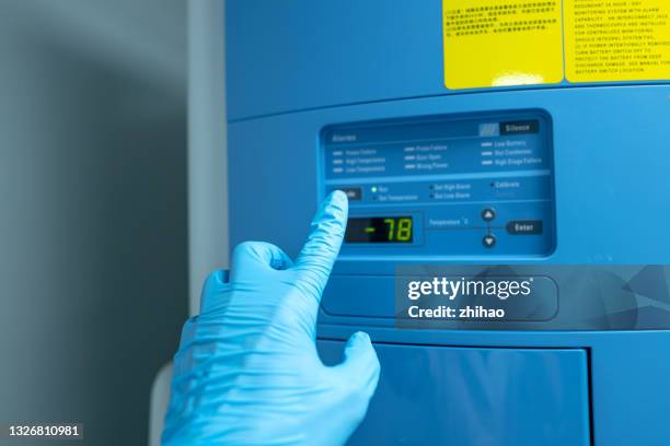 hand wearing protective gloves to operate ultra-low temperature refrigerator - cryobiology stock pictures, royalty-free photos & images