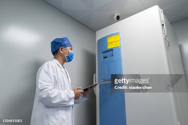 low angle view of asian male doctor holding tablet computer for work - cold storage room stock pictures, royalty-free photos & images