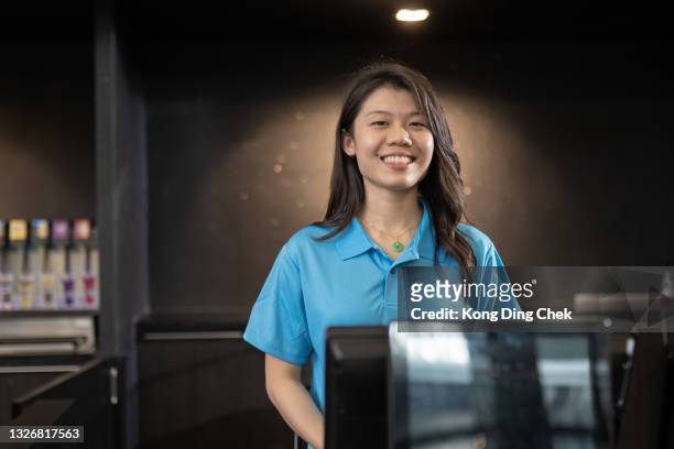 trabajador de entradas de cine chino asiático con uniforme mirando a la cámara sonriendo frente al puesto de concesión en el cine de cine - like a boss film fotografías e imágenes de stock