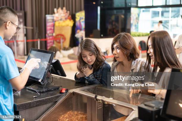 group of asian chinese women in front bar counter ordering popcorn before movie show time at movie theater cinema - movie counter stock pictures, royalty-free photos & images