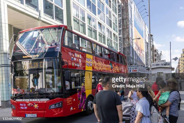 Double-decker tourist bus drives past Checkpoint Charlie, the best-known Berlin Wall crossing point between East Berlin and West Berlin during the...