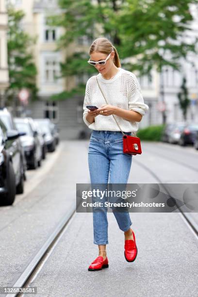Influencer and model Marlies Pia Pfeifhofer wearing a white mesh pullover by Sweaty Betty, light blue denim jeans pants by Closed, a red bag with a...