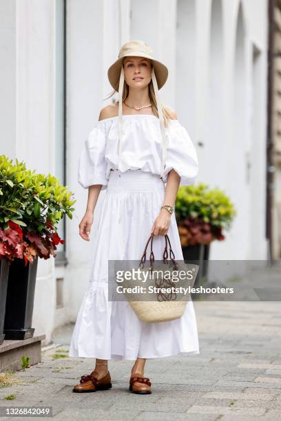 Influencer and model Marlies Pia Pfeifhofer wearing a white off shoulder cropped top with puff sleeves by Tory Burch, a white maxi skirt by Tory...