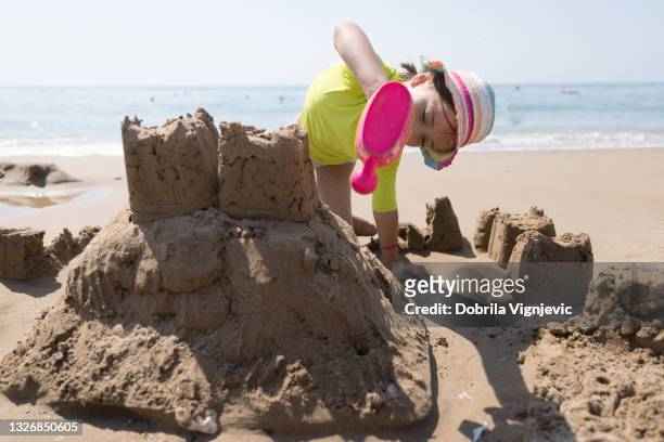 mädchen spielen mit gießkanne und dem sand - kind sandburg stock-fotos und bilder