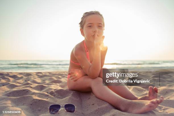 child silencing people on the beach with finger on her lips - finger on lips stock pictures, royalty-free photos & images