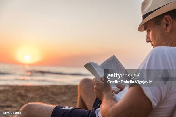 man reading a book at the beach - beach book reading stockfoto's en -beelden