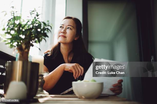 asiatische seniorin arbeitet zu hause mit einem laptop - finanzplanung stock-fotos und bilder