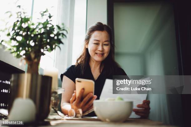 asian senior woman working at home with a laptop - choosing insurance stock pictures, royalty-free photos & images