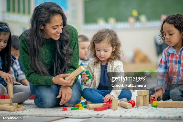 preschool children playing with wooden blocks - child care stockfoto's en -beelden