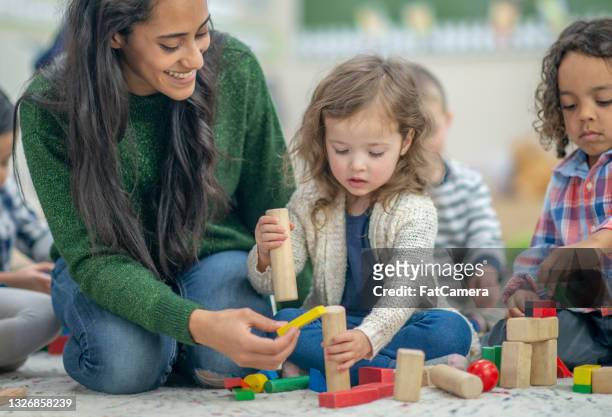 preschool children playing in a classroom with a teacher - montessori education stock pictures, royalty-free photos & images
