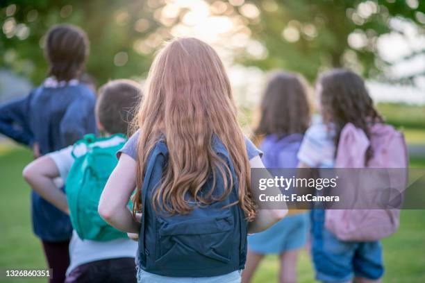 elementary students carrying their backpacks - no face stockfoto's en -beelden