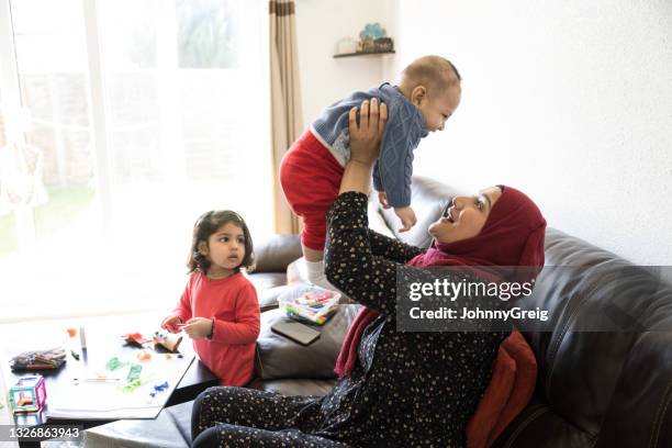 madre asiatica britannica dei primi anni '30 che gioca con il figlio a casa - muslim family foto e immagini stock