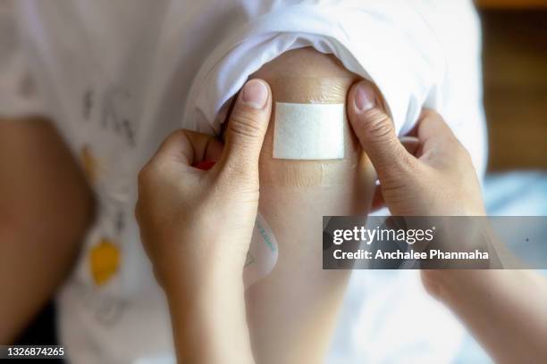 health & medical concept: a doctor applying a plaster cover after injecting a patient in her arm - wunde stock-fotos und bilder