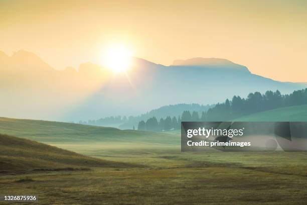 sunlight shining over alpe di siusi  and lush field at mountain group in background ,dolomites italy - church sunset rural scene stock pictures, royalty-free photos & images