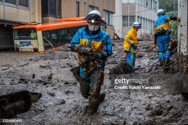 Police officer with a search and rescue dog, searches the area around the site of a landslide on July 04, 2021 in Atami, Shizuoka, Japan. Torrential...