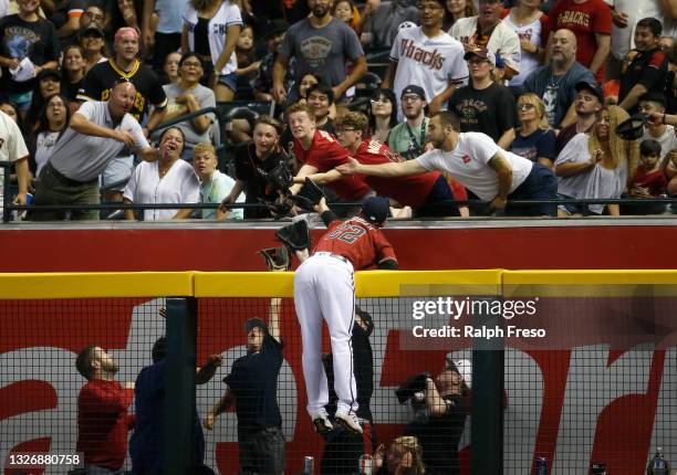 Right fielder Josh Reddick of the Arizona Diamondbacks leaps above the fence, reaching into the crowd, in an attempt to catch a home run ball hit by...