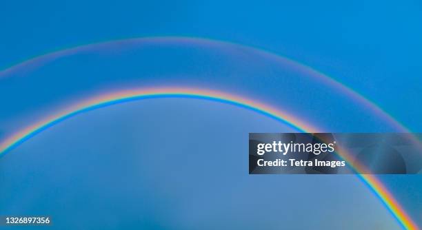 double rainbow on blue sky - arco iris doble fotografías e imágenes de stock