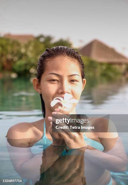 thailand, koh samui island, portrait of smiling woman holding frangipani flower in water - frangipani stock pictures, royalty-free photos & images