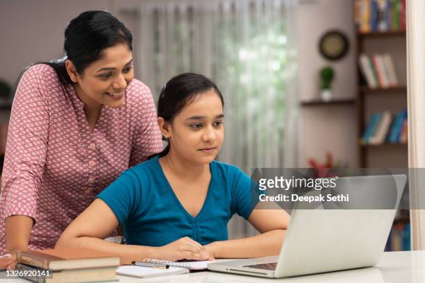 teenage girl using laptop while studying with her mother at home:- stock photo - parent stock pictures, royalty-free photos & images