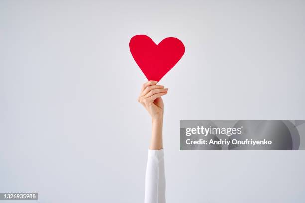 female's hand holding red heart against white grey background. - assistant photos et images de collection