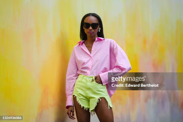Emilie Joseph @in_fashionwetrust wears A pastel baby pink boyfriend shirt, high waisted cutoff denim ripped shorts with fringes in lime green / neon...