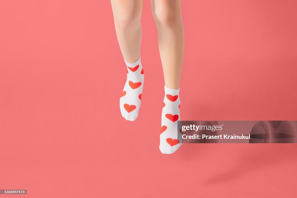 Woman feets in warm socks with a hearts print on white background