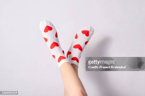 woman feets in warm socks with a hearts print on white background - socks fotografías e imágenes de stock