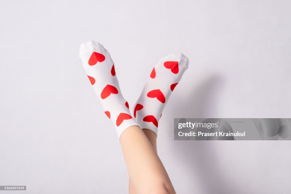 Woman feets in warm socks with a hearts print on white background