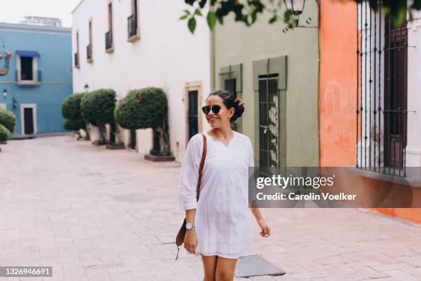 woman with sunglasses walking on urban street in mexico - ville de queretaro photos et images de collection