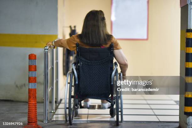 femme en fauteuil roulant entrant dans un immeuble - paraplegic woman photos et images de collection