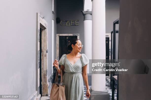 woman walking towards the camera carrying shopping bags, looking sideways - bundesstaat queretaro stock-fotos und bilder