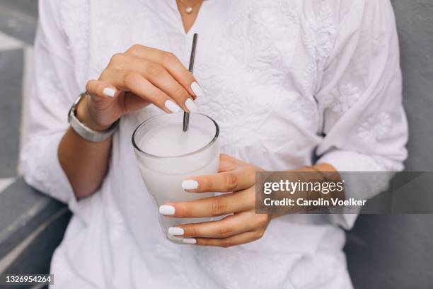 female hands touching a metal straw and holding a white drink - metal straw stock pictures, royalty-free photos & images