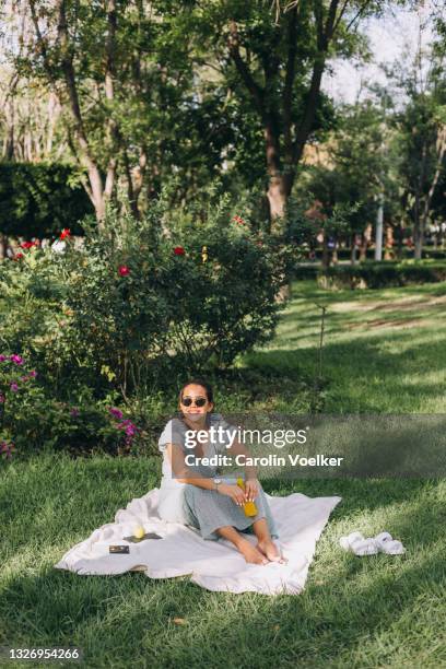 woman holding a drink during a picnic in a park - mexican picnic stockfoto's en -beelden